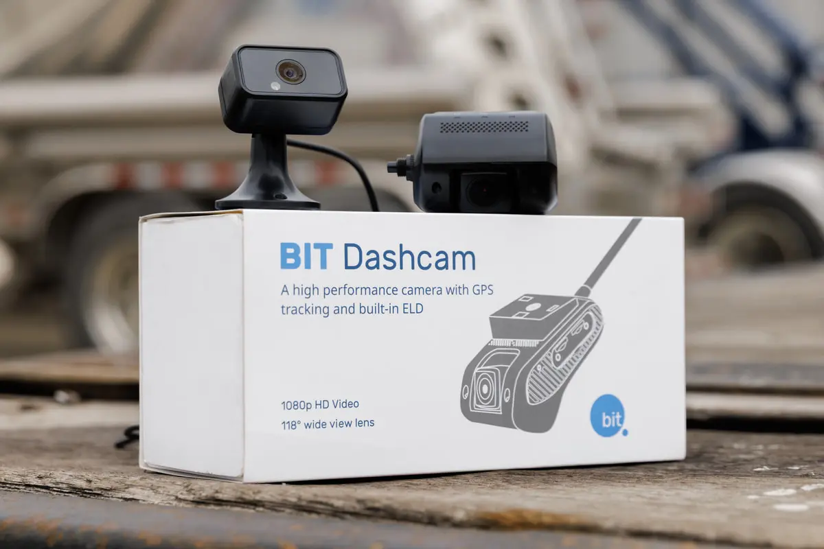 The BIT Dashcam and the optional driver-facing camera on their box, outside in a truck yard